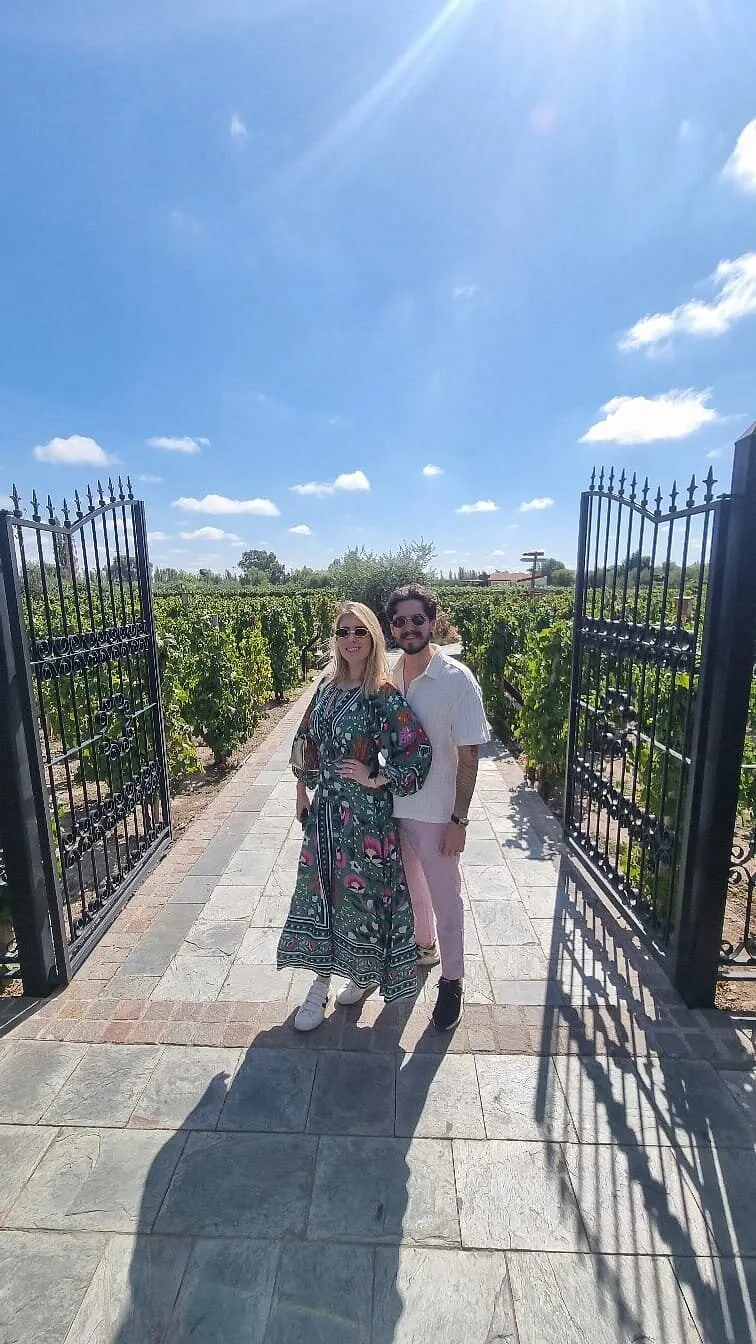 Casal em vinícola com vinhedos ao fundo